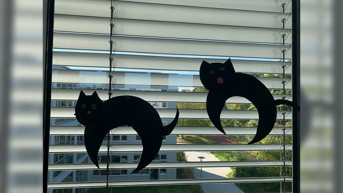 Bild: Schwarze Katzen aus Pappkarton zieren das Fenster