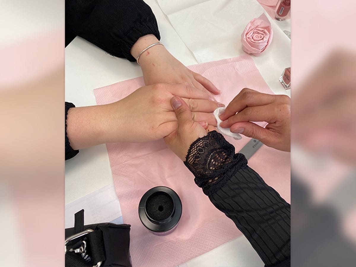 Die Kosmetikerin führt an einer Schülerin ein Handpeeling durch.
