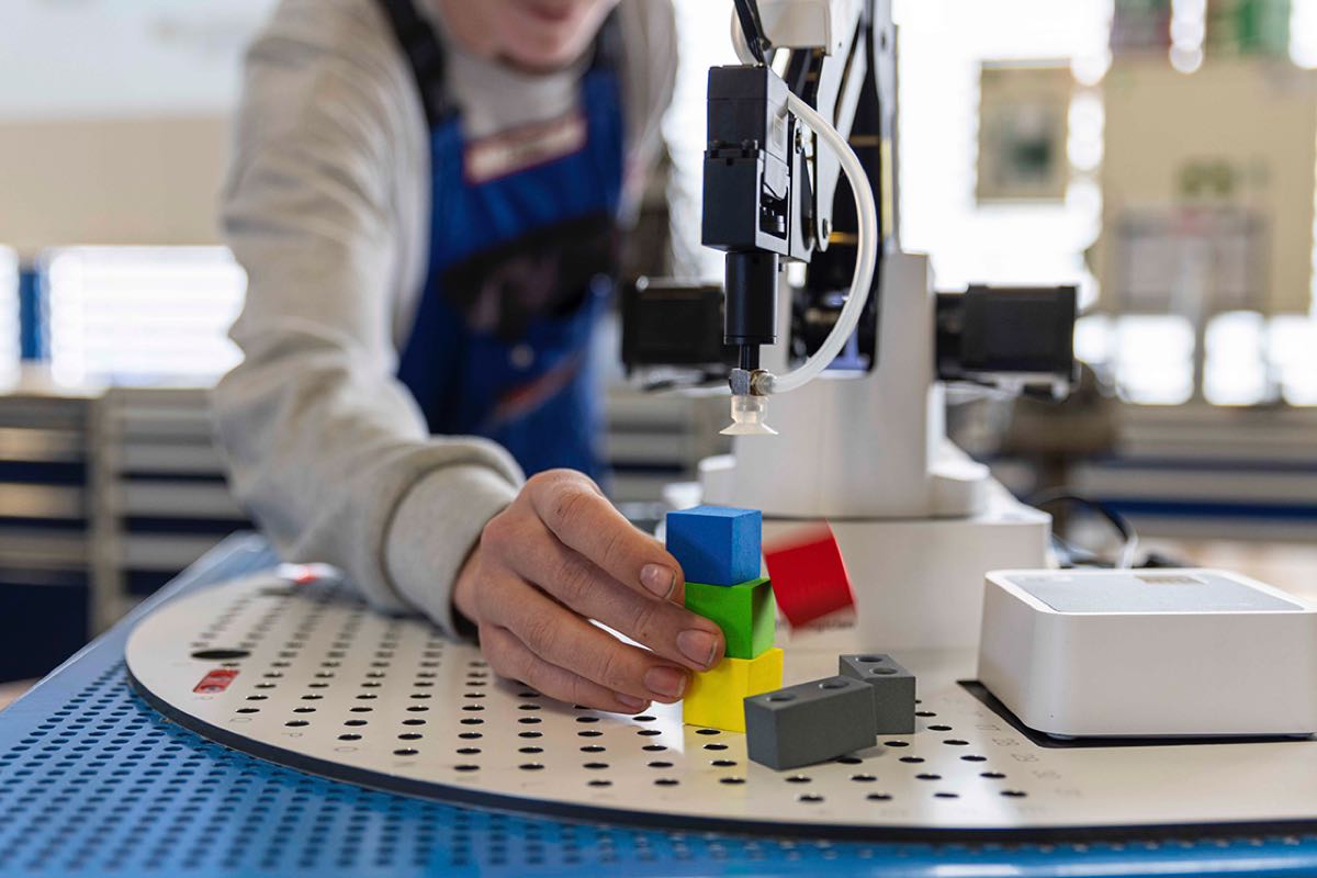 Ein junger Mann, der an einem wissenschaftlichen Gerät arbeitet und vier verschiedenfarbige Klötzchen darunter platziert.