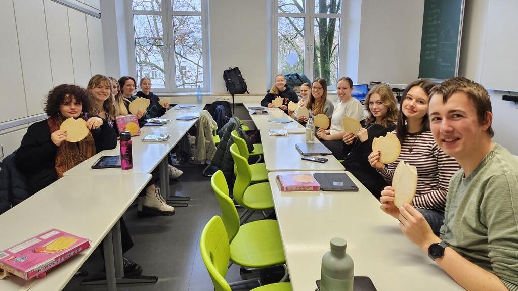 Bild: Schülerinnen und der Student Rob sitzen zusammen in einem Klassenzimmer.